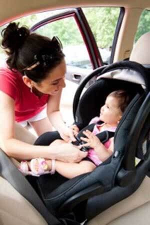 A mother strapping her baby into a car seat