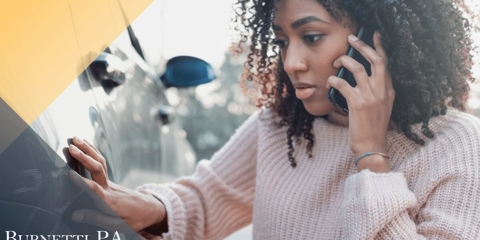 woman on her phone looking at vehicle damage