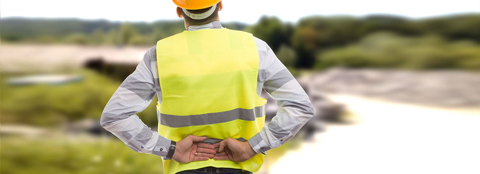 A construction working standing on a jobsite holding his back