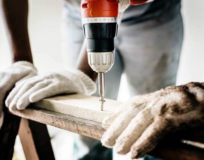 worker drilling while wearing protective gloves