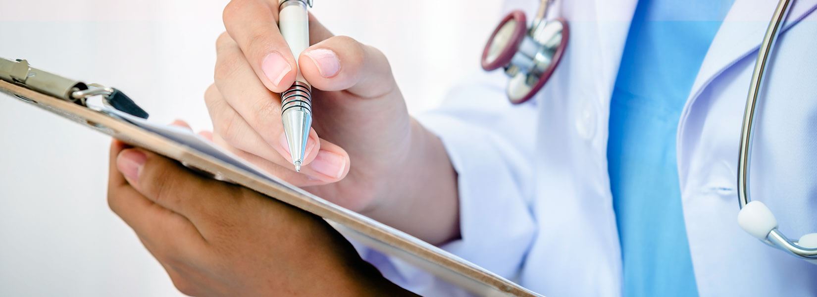 Doctor filling out paperwork on a clipboard