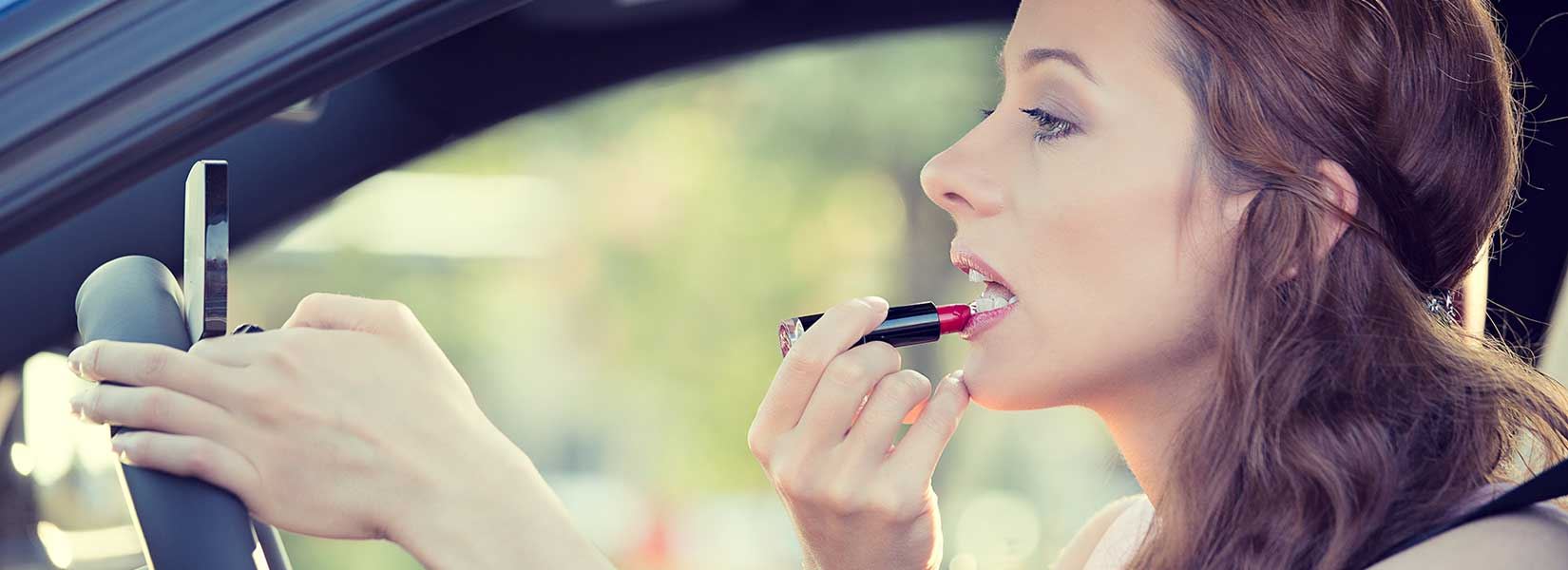 Woman putting on lipstick while driving a car