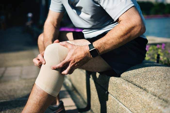 A man wearing knee brace holding his knee