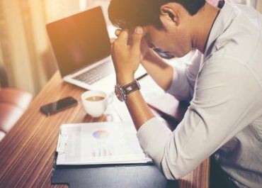 man leaning on a desk with his hands on his forehead