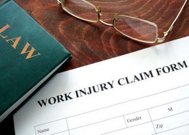law book, classes and work injury claim form on a desk