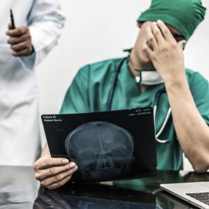 Man holding his head while holding a skull x-ray