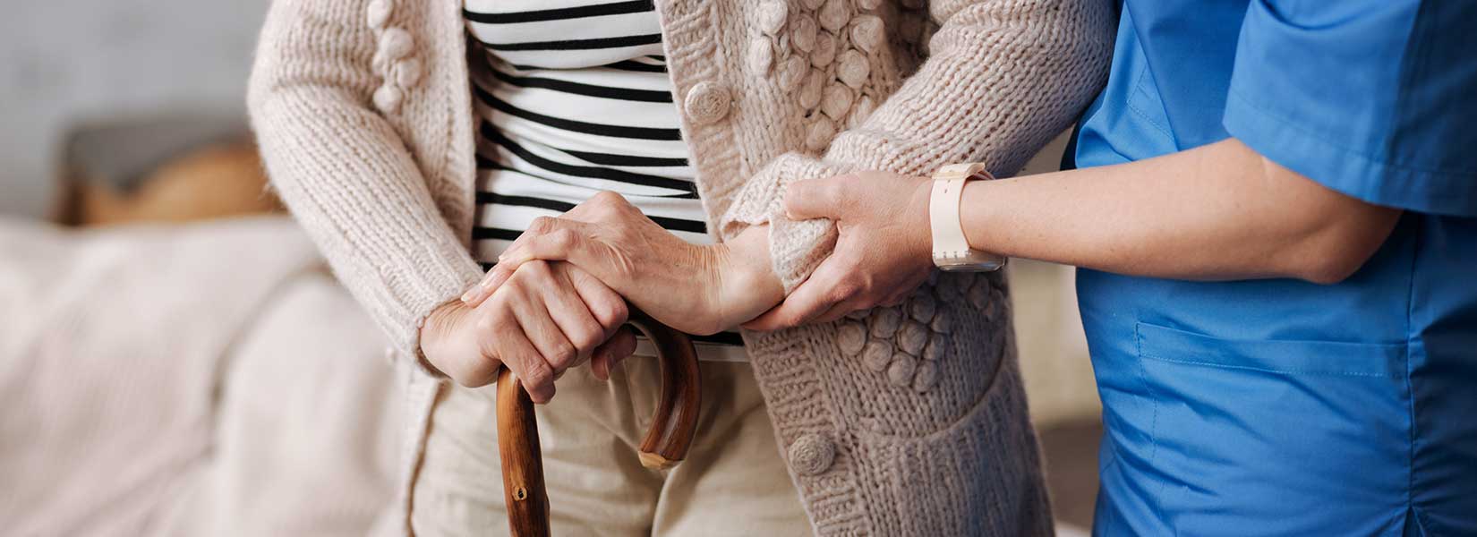 Lady assisting an elderly person holding a cane